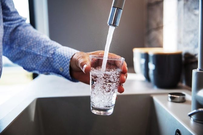 水道水をコップに注いでいる手元