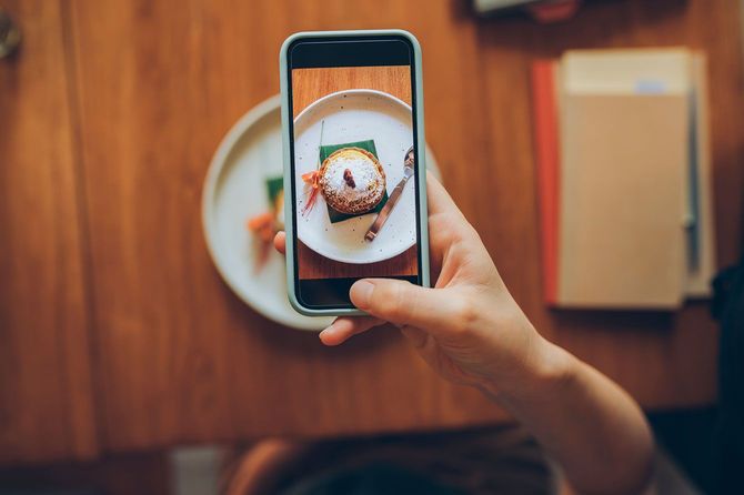 カフェでケーキの画像を撮影する人の手元