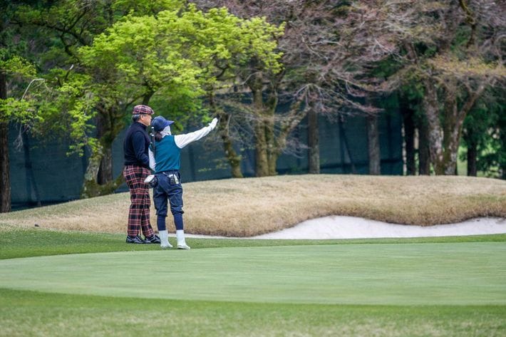 キャディは常にコースガイドを持ち、<wbr></wbr>正しい距離を伝えるよう心掛けているという