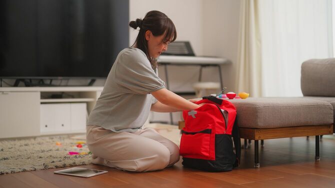 自宅で非常用バッグを準備する女性