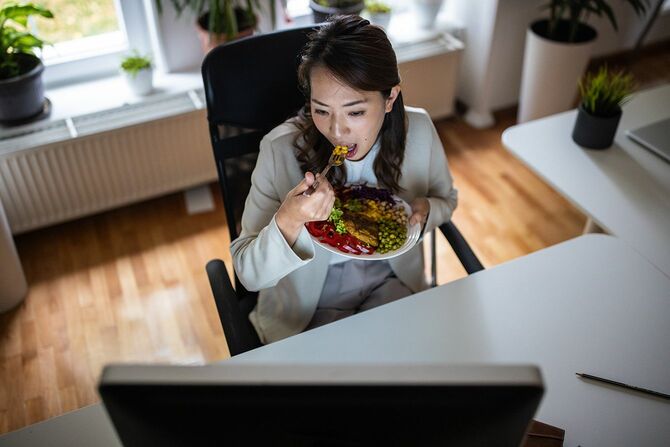 健康的な食事を食べながらオフィスで働く日本人女性
