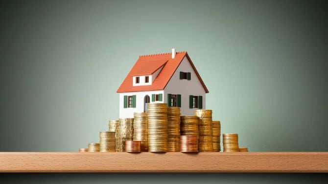 ミニチュアの家の周りに積み上げたコイン