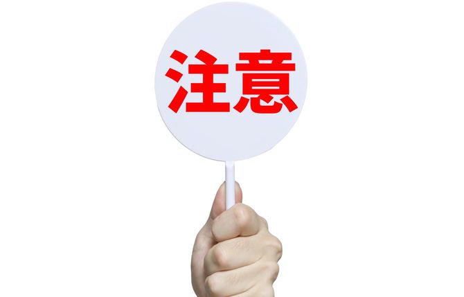 「注意」と書かれた札を持つ手元
