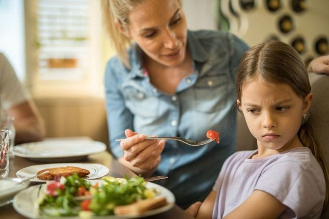 嫌がる子供に食べさせようとする母親