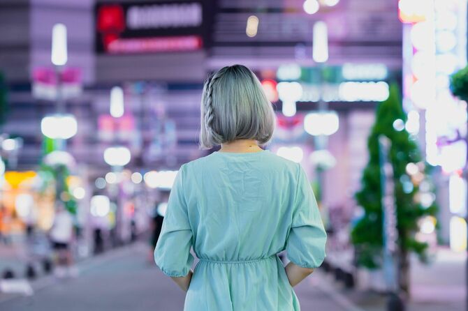 夜の東京の繁華街に立つ女性