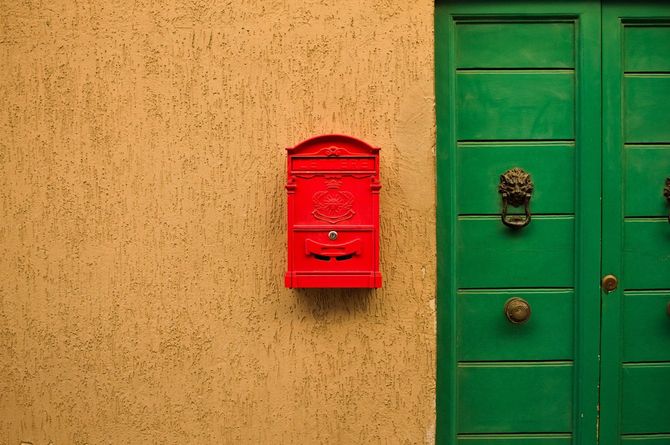 緑色の扉の横に赤い郵便受け