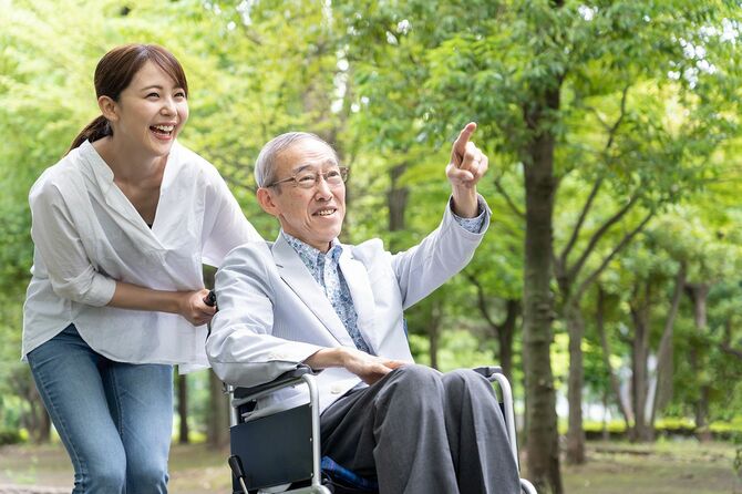 公園で車椅子を持つ若いアジアの女性と老人の男性