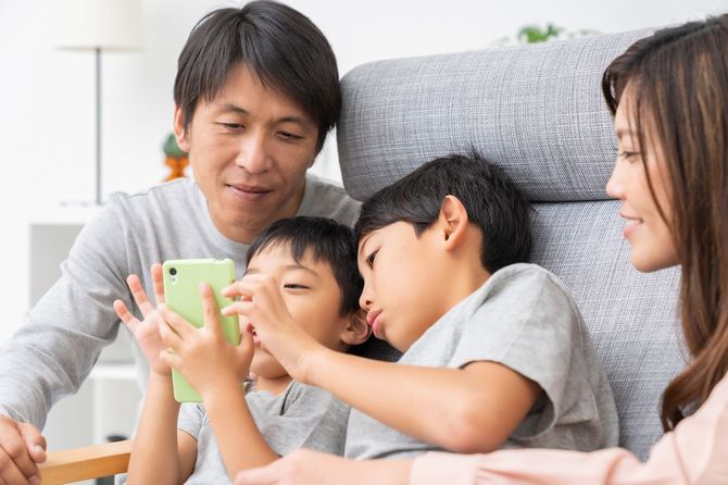 スマートフォンを見ている4人家族