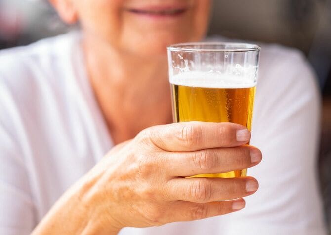 ビールを注いだコップを手に持つ笑顔の高齢女性