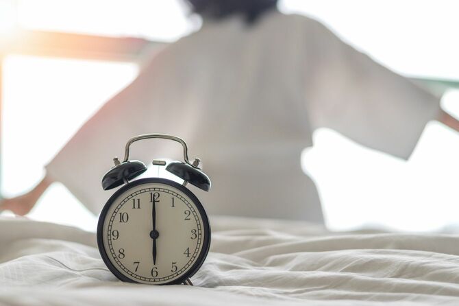 ベッド上のアラーム時計と女性