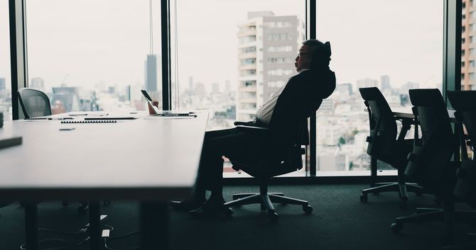 オフィスチェアーにすわったまま休憩している男性