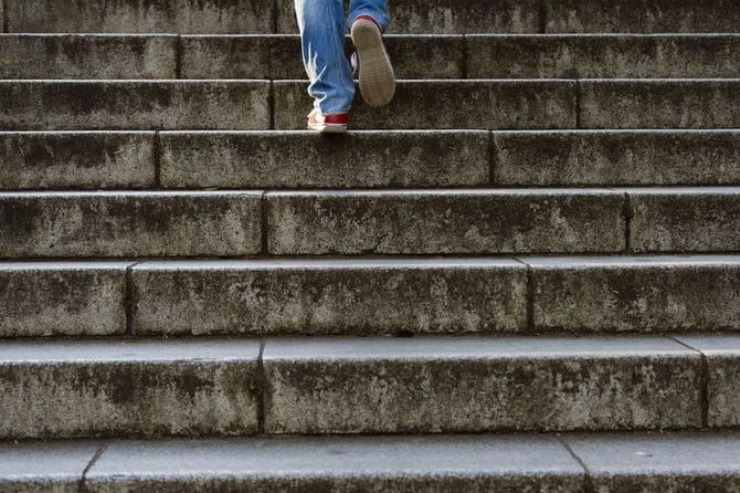 ジーンズと赤いスニーカーを履いて階段を上る男