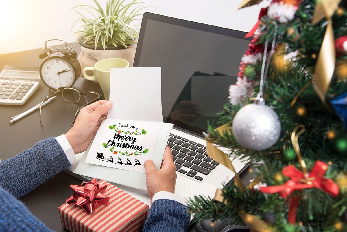 オフィスのデスクで、もらったクリスマスプレゼントとメッセージカードを見ている男性