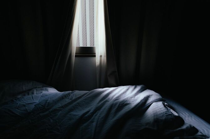 少しだけ開いたカーテンから光が差し込む暗い寝室