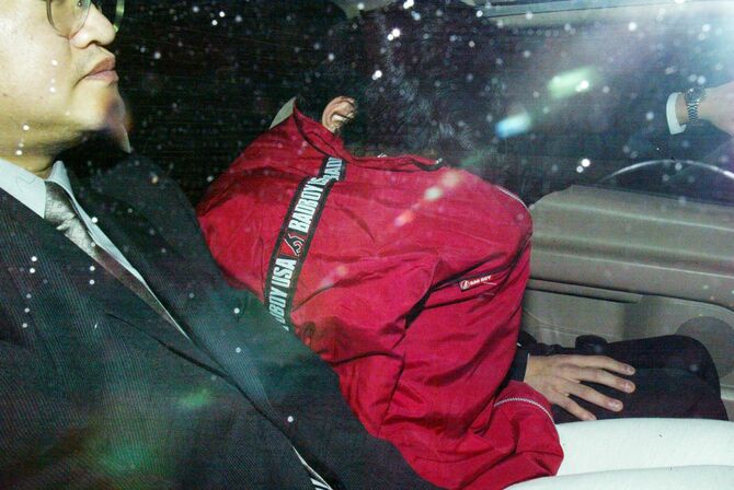 建造物侵入容疑で逮捕され、送検される住所不定、無職の山地悠紀夫容疑者(赤い服)(=2005年12月6日、大阪市浪速区の浪速警察署)