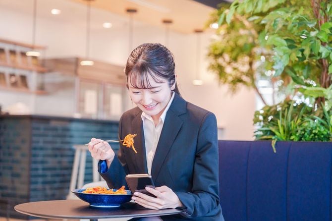 スマホを片手に楽しくランチをするビジネスウーマン