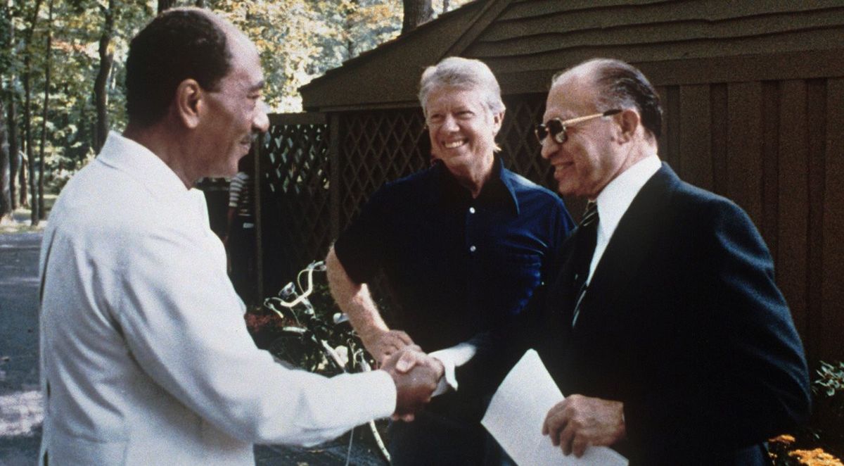 1978年9月、握手を交わすイスラエル首相メナヘム・ベギン氏とエジプト大統領アンワル・サダト氏、中央は米国大統領ジミー・カーター氏