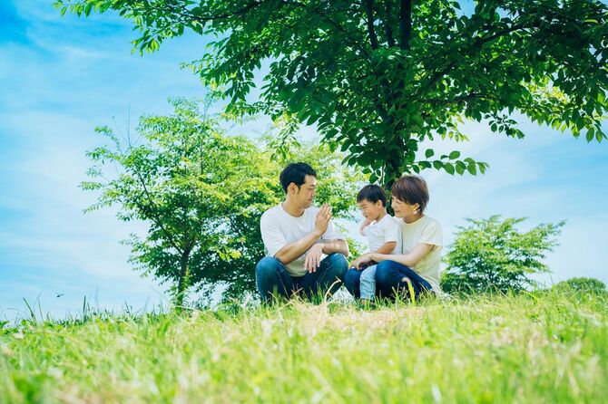 日当たりの良い緑地に座る親と子供