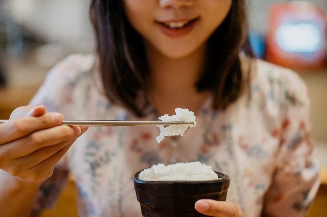 白米のボウルを食べる笑顔の若いアジアの女性