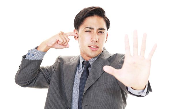 ストレスを感じるビジネスマンが片耳をふさいでいる