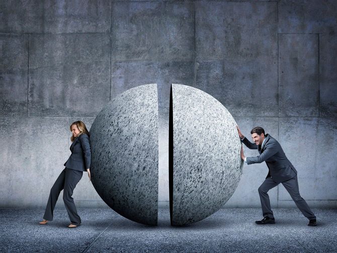 真っ二つに割れた大きなコンクリートの球体を押し戻そうと奮闘するビジネスマンとビジネスウーマン