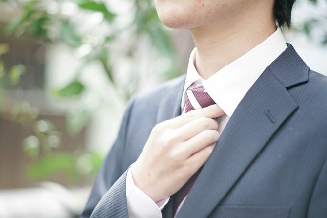 ネクタイに手を置くスーツを着たビジネスマン