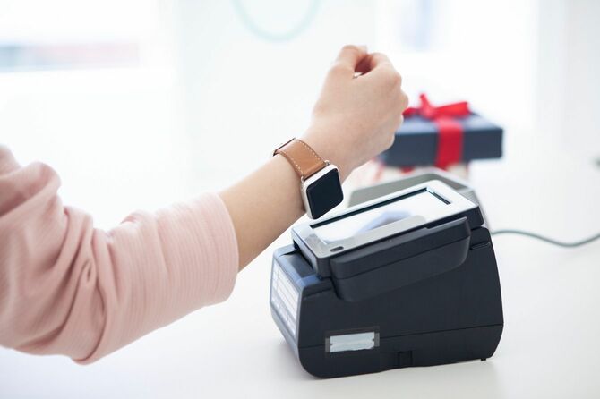 右手につけたスマートウォッチで決済をする人