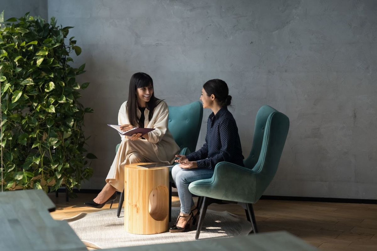 椅子に座って会話を楽しむビジネスパーソン二人