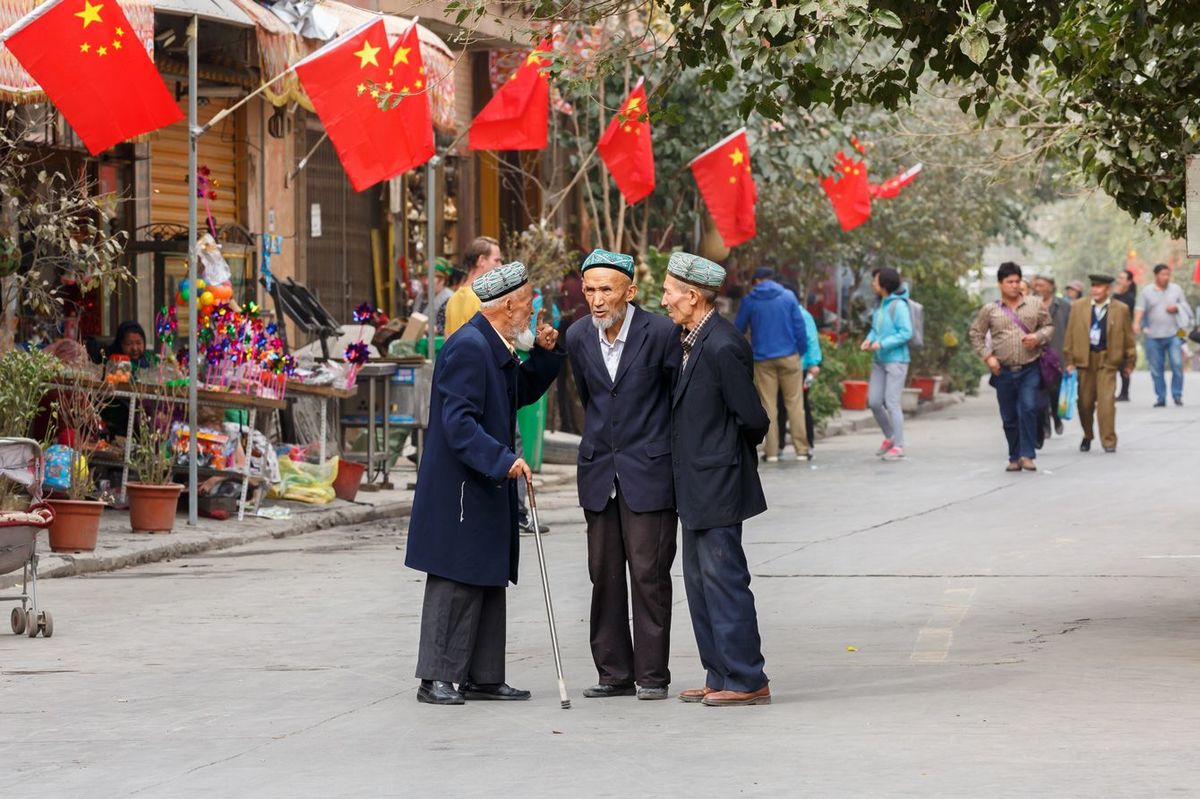 ウイグル人の3人の高齢男性がカシュガル旧市街の通りで会話をしている