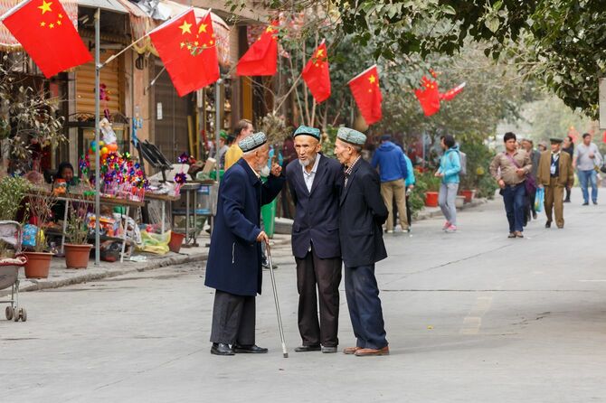 ウイグル人の3人の高齢男性がカシュガル旧市街の通りで会話をしている