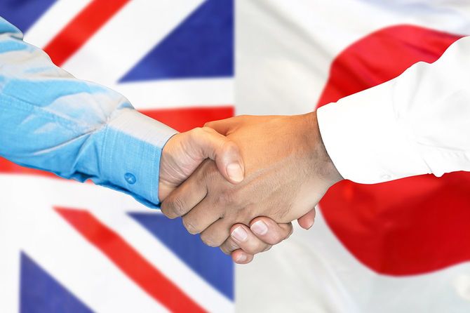 イギリスと日本の旗を背景に握手