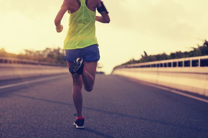 街の道路で走っている若いフィットネス女性