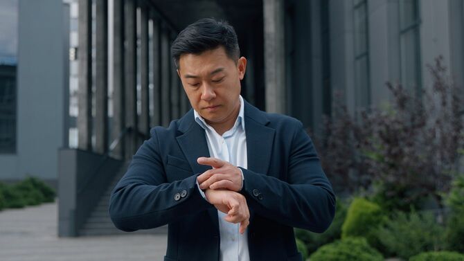 腕時計で時間を確認する男性