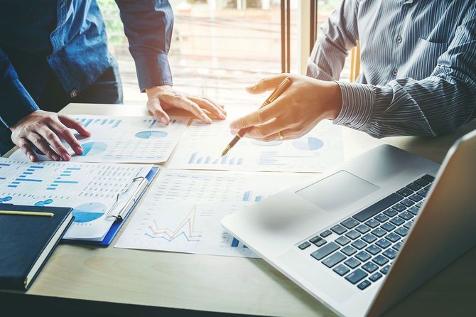 資料を広げ打ち合わせをする2人のビジネスパーソン