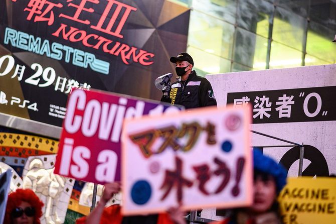 新型コロナウイルスの感染症対策などに抗議し、プラカードを掲げてデモをする人たち