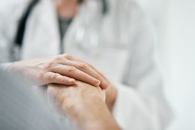 患者の手を握る医師
