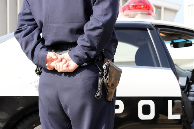 パトカーの傍らに立つ警察官