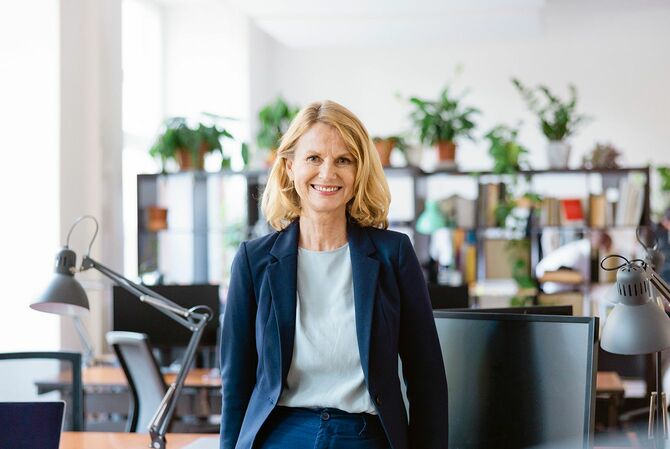 オフィスの机のそばに立つ笑顔の女性