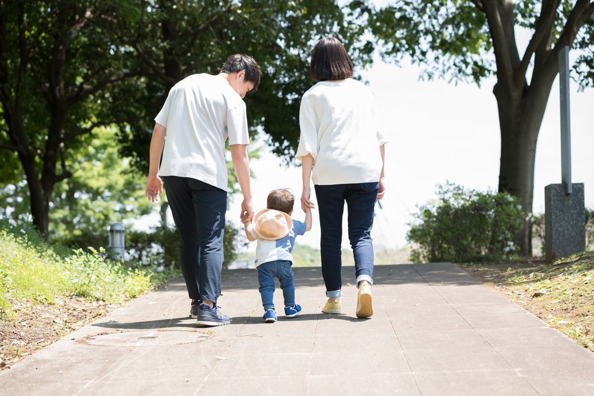 手をつないで歩く3人の家族