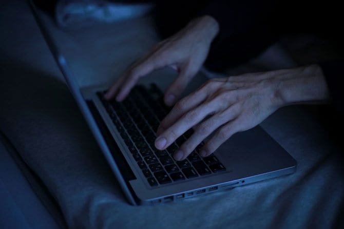 暗い部屋でパソコンを使用する人の手元