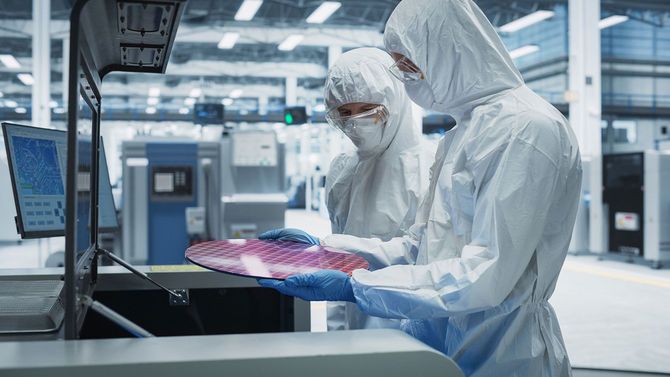 シリコンウエハーをチェックする半導体工場の作業員