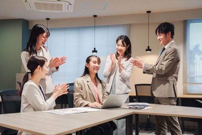 オフィスのメンバーから拍手を受ける女性社員