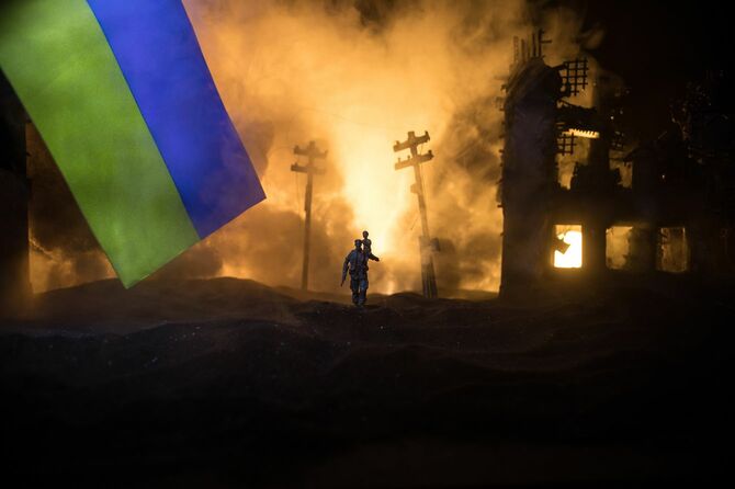 ウクライナ国旗と戦火の街を歩く人影