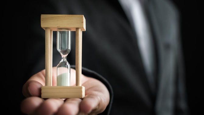 ビジネスパーソンの手の上に砂時計
