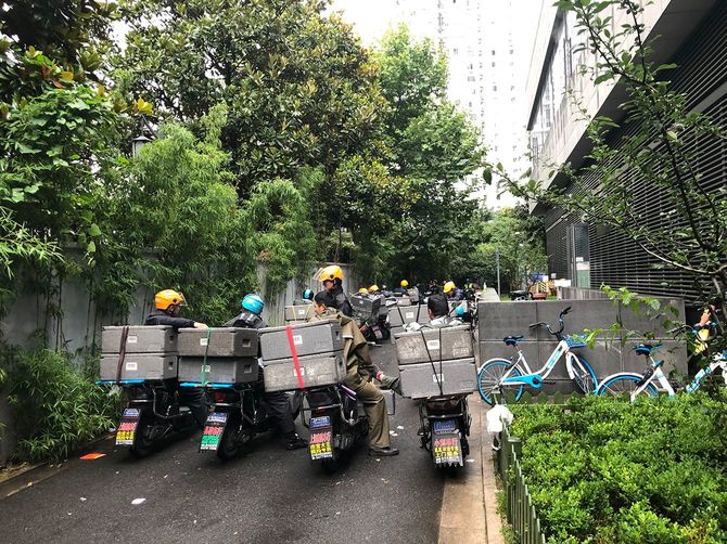 電動バイクにまたがった多数の配達員