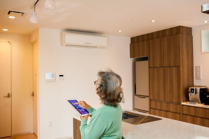 スマート家電を使って電気をつける年配の女性