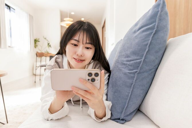 若い女性が自分の部屋でスマートフォンを使っている
