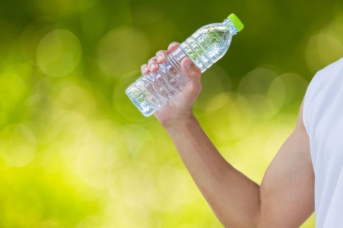 ぼやけたボケの背景にペットボトルを持っている男