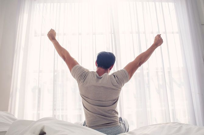 朝起きて伸びをする男性