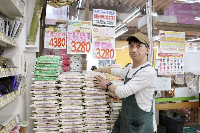 スーパー「フレッシュ市場 マルフク中浦和本店」の店頭に積まれたコメと福島晶彦店長=2026年4月23日、さいたま市
